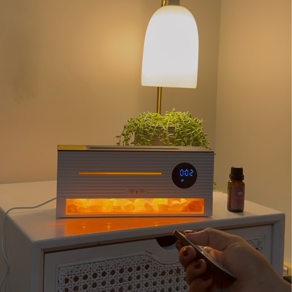Amber Glow Flame Diffuser with clock display, remote control, and essential oil bottle on bedside table