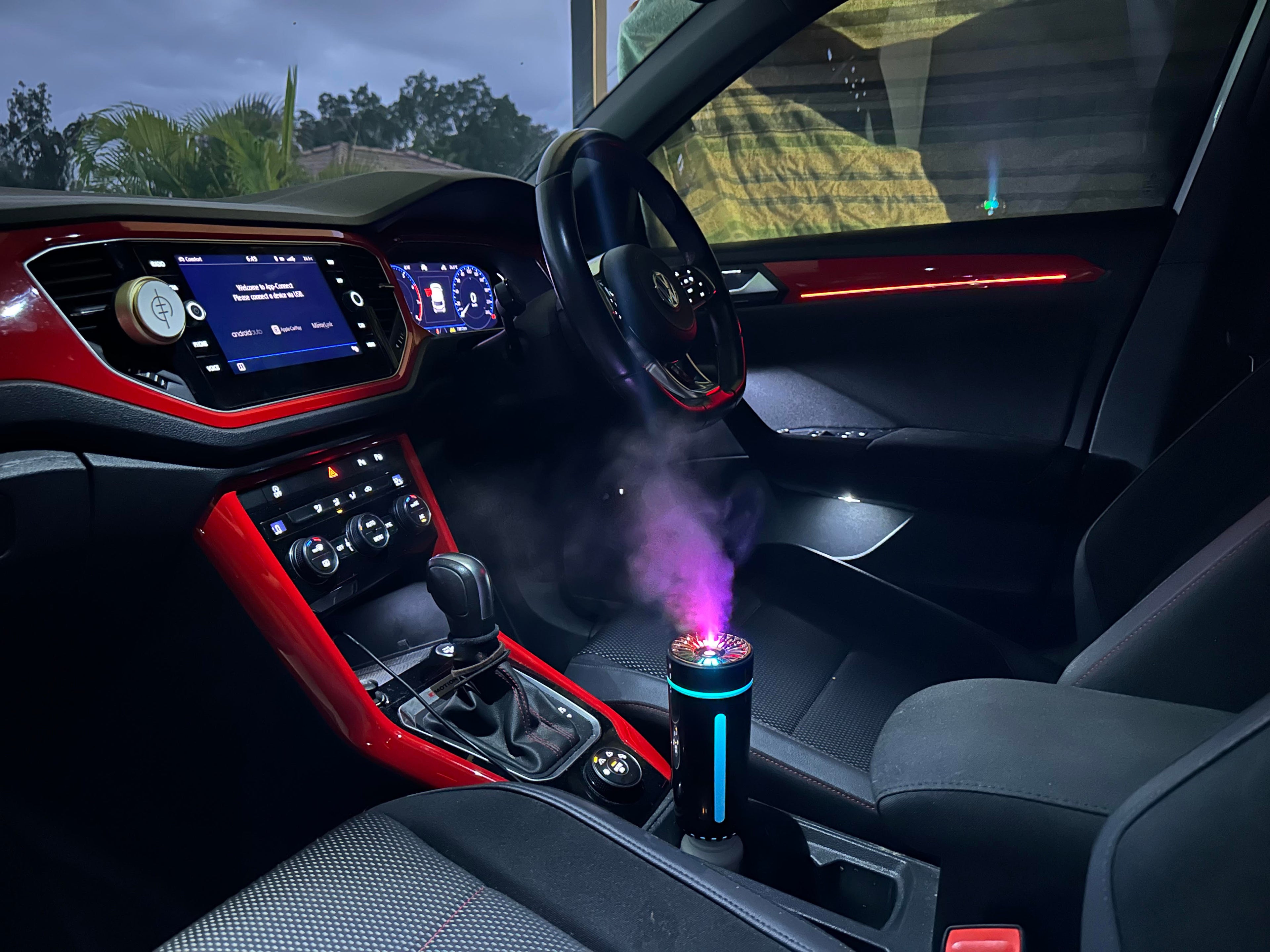Illumaluxe portable car diffuser releasing mist inside a modern vehicle – essential oil aromatherapy on the go
